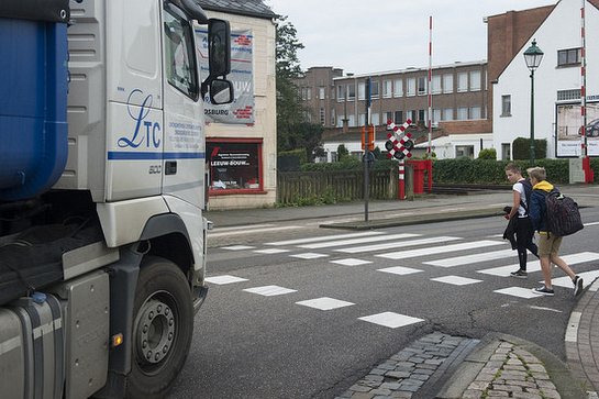 twee jongens steken over op het zebrapad, een vrachtwagen wacht