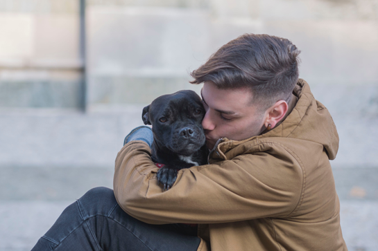 Een man omhelst een hond.